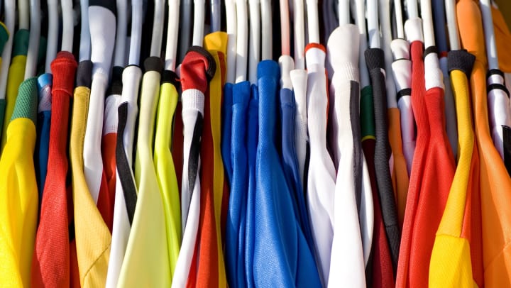 A series of colorful sports jerseys on white clothing hangers