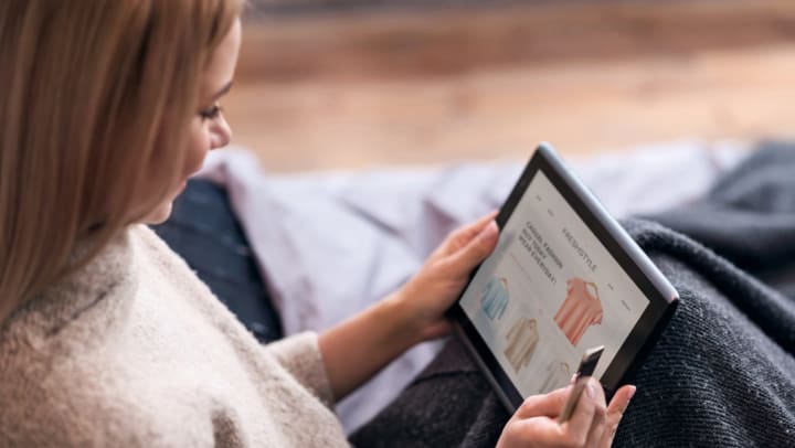 Woman online shopping using a tablet and credit card while sitting in bed