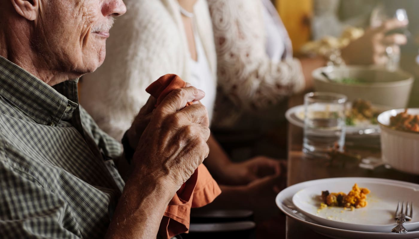 A close-up view of an elderly man holding a napkin at the dining table with empty plate at The Pillars of Prospect Park in Minneapolis, Minnesota