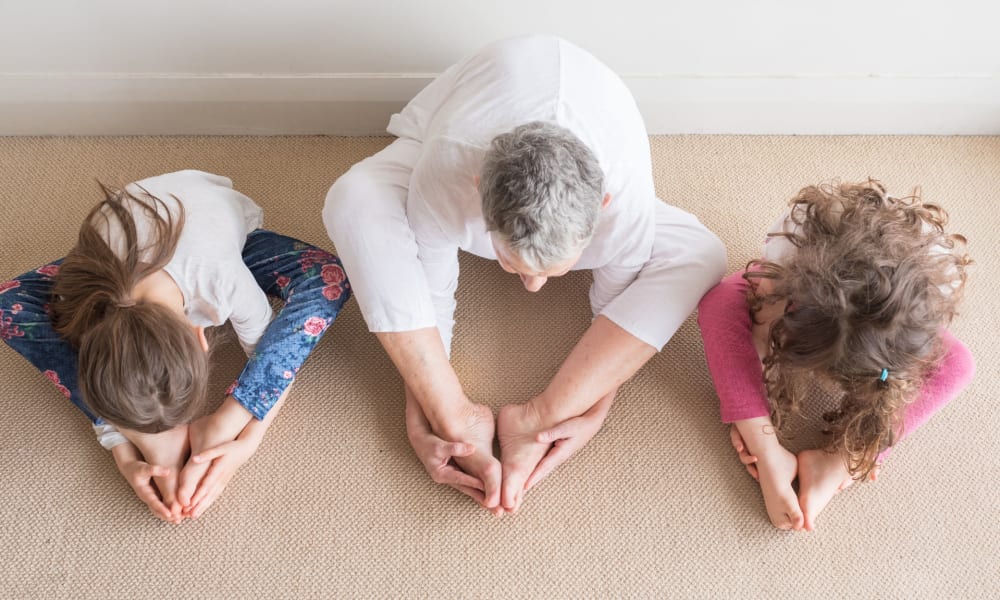 A resident and two children practicing yoga at Amaran Senior Living in Albuquerque, New Mexico. 