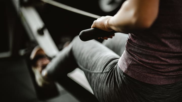 Close-up of a woman wearing fitness clothes and rowing on a rowing machine