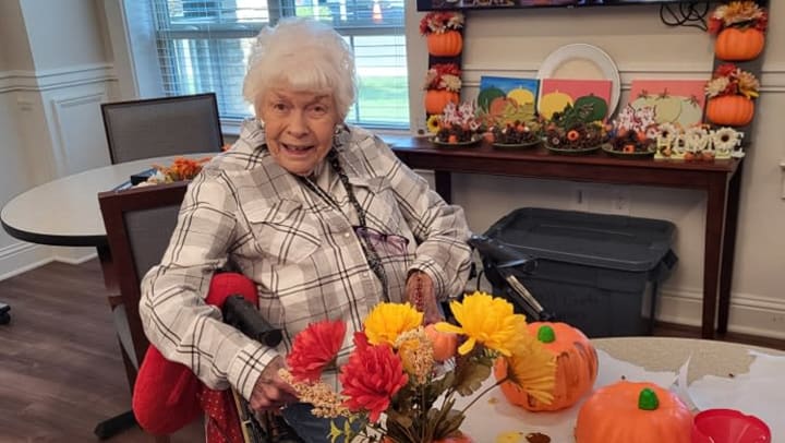 senior woman next to painted pumpkins 