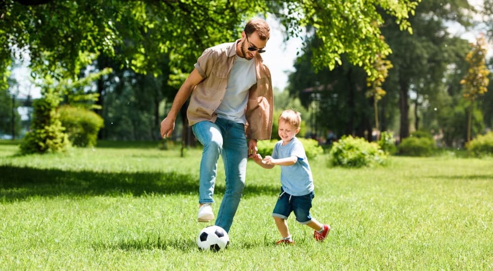 Resident father and son playing soccer in the green areas surrounding The Cordelia in Fort Walton Beach, Florida