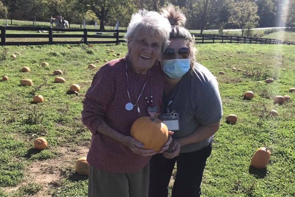Resident and a caretaker at a pumpkin patch at English Meadows Lexington Campus in Lexington, South Carolina