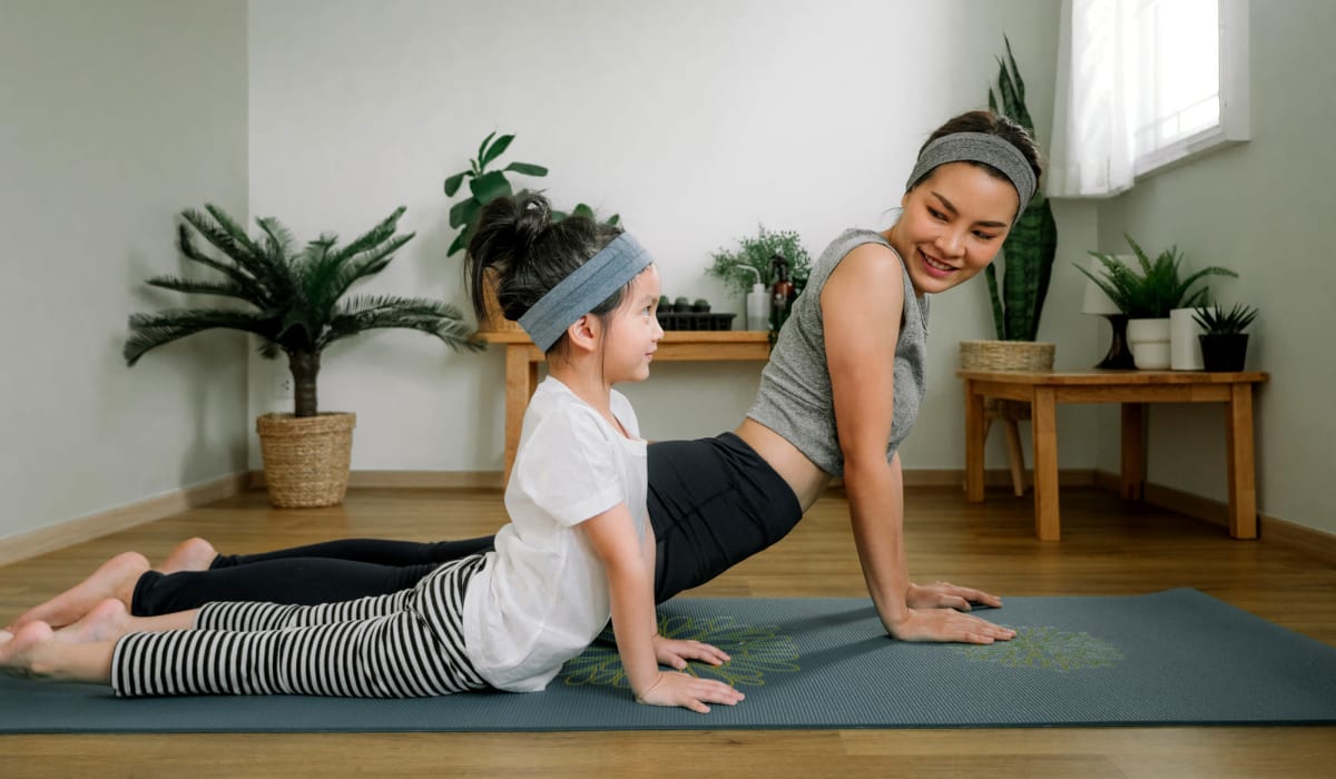 Mom and daughter doing yoga in their living room at Neponset Landing in Quincy, Massachusetts