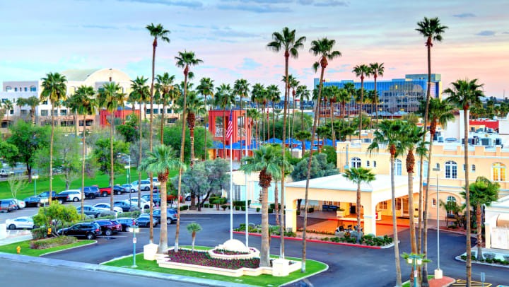 View of city skyline with palm trees, colorful buildings, and green space