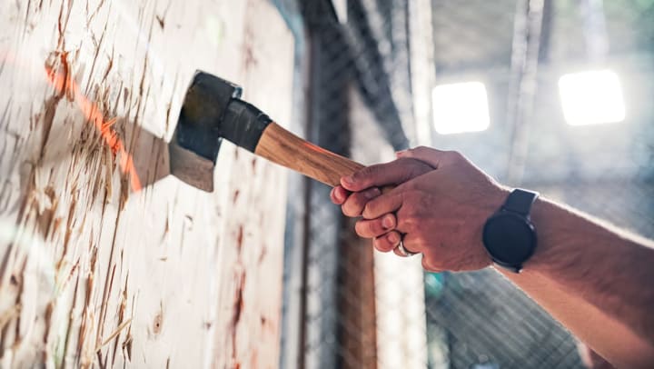 A close-up of hands grabbing an axe handle after throwing it at the target | axe throwing around Keller