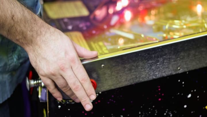 Person playing pinball near {{location_name}} in {{location_city}}, {{location_state_name}}