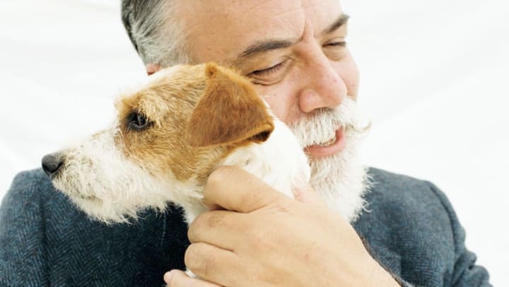 Older man smiling and hugging Jack Russell Terrier