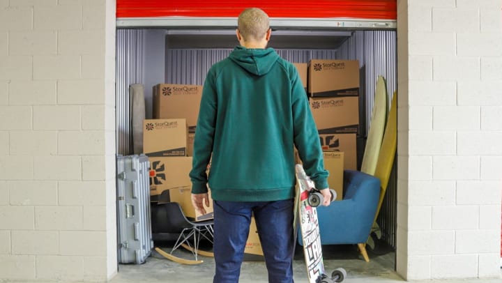 College student holding skateboard looking at storage unit