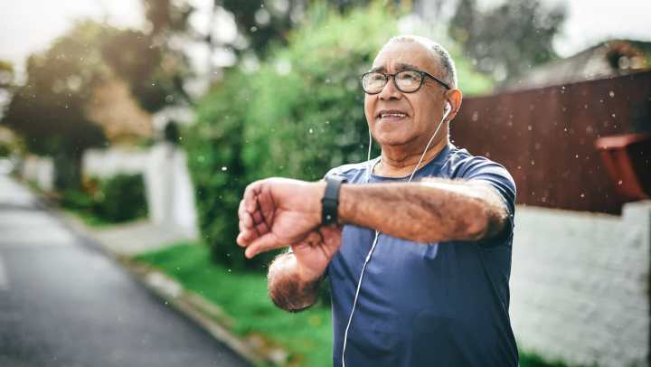 Man jogging while checking his smartwatch.
