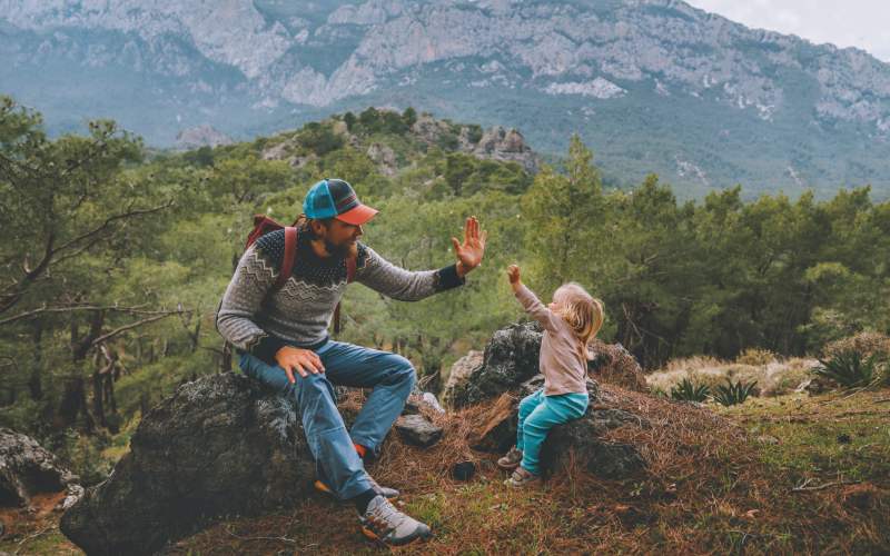 A father and daughter high fiving on a hiking trail near Ascent at Lowry in Denver, Colorado