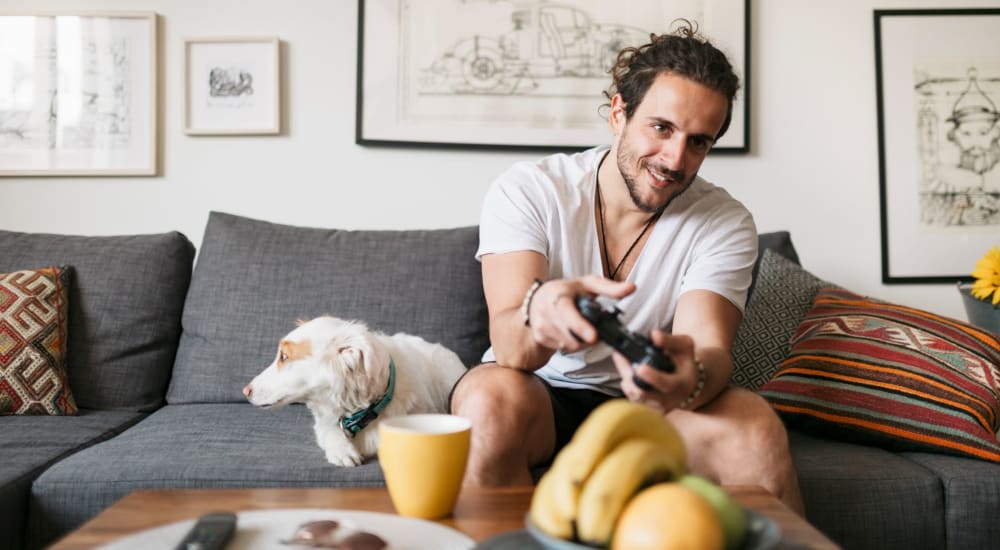 Resident gaming with his dog keeping him company in their pet-friendly home at Eight Mile House in Stockton, California