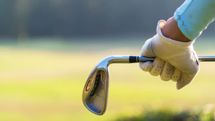 Close-up of a golfer holding an iron behind their body