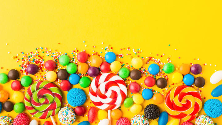Colorful candies over yellow background. Top view. Flat lay.