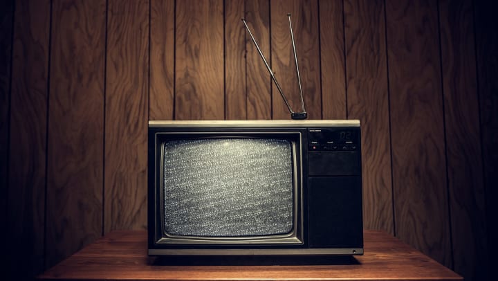 Vintage TV with static on the screen, wood paneling in the background. 
