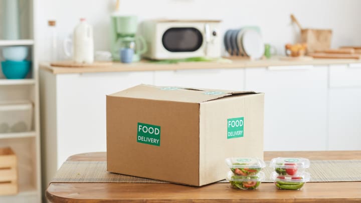 A large cardboard box that reads, “Food Delivery” sitting on a kitchen counter.