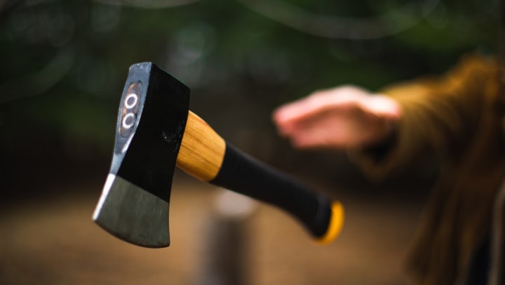 Axe in the air with a blurry hand in the background.