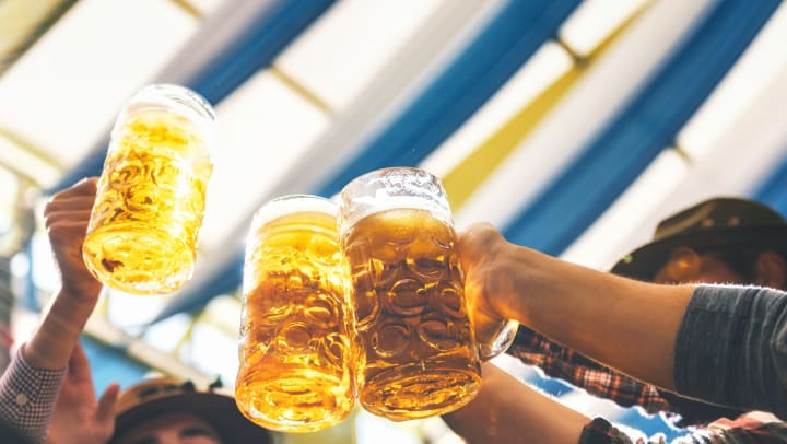 Several hands raise a toast with large, glass beer steins at Oktoberfest.
