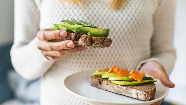 Close-up of woman holding plate with avocado toast