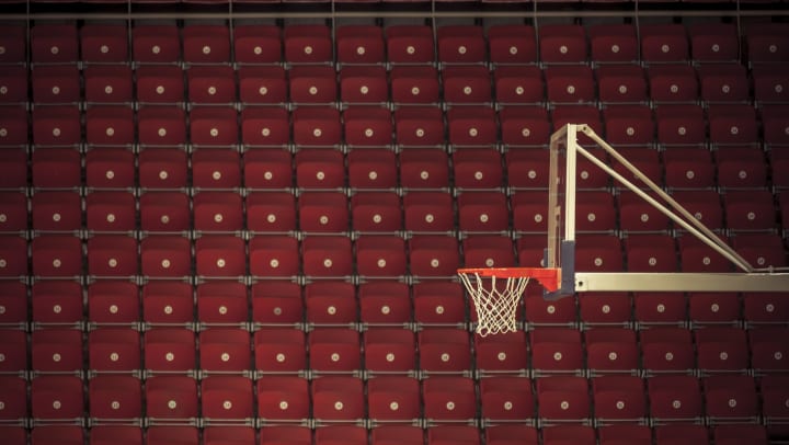Basketball hoop against a backdrop of red seats in an arena