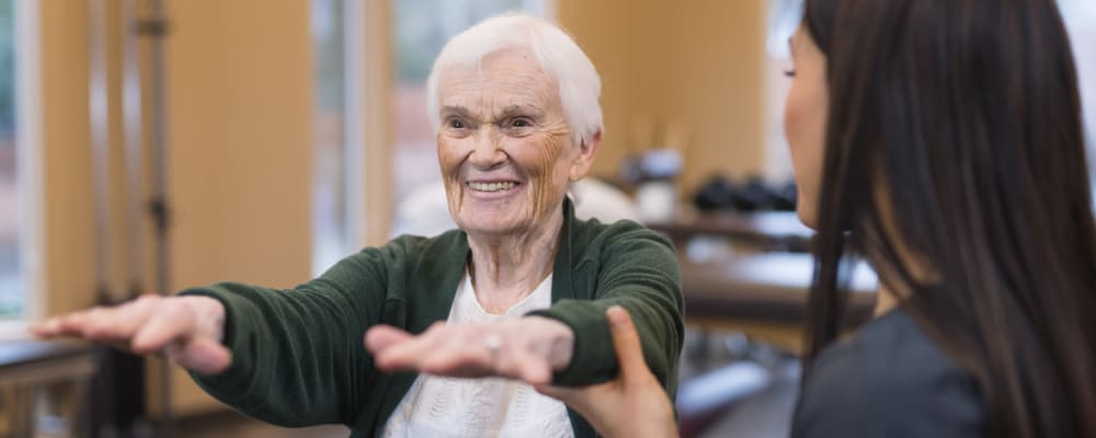A resident smiling while exercising with a staff member at Ridgeline Management Company in Rockwall, Texas