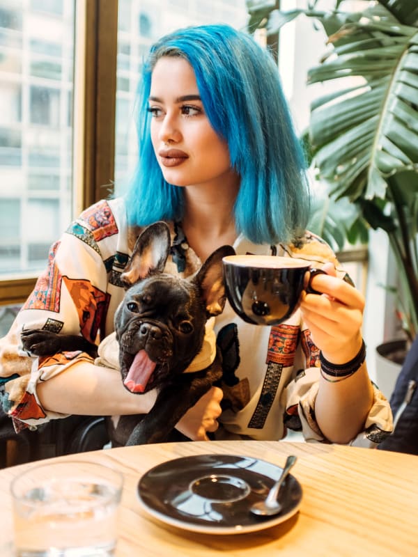 Woman holding her dog and drinking coffee at Bellrock Bishop Arts in Dallas, Texas