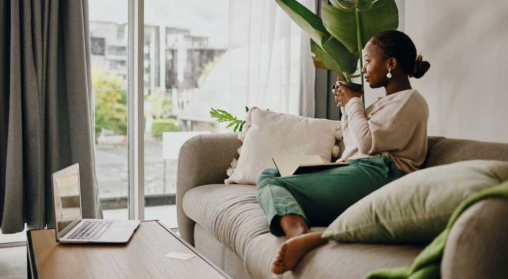 Resident relaxing and sipping coffee in a spacious living room at East National Flats in Milwaukee, Wisconsin     