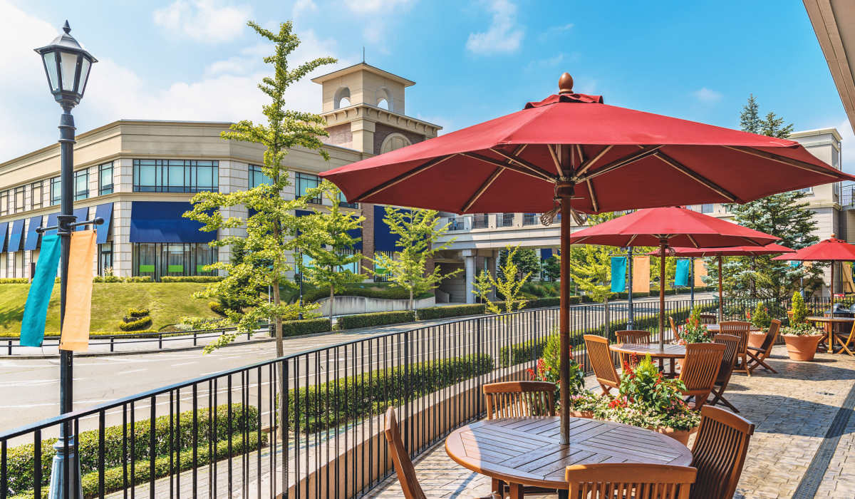 Outdoor patio with red umbrellas and landscaped greenery in a vibrant community setting at Palatine Meadows in New Bern, North Carolina