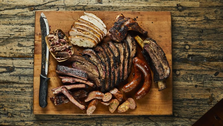 Top-down view of a platter of grilled meats including brisket, sausage, ribs, and chicken