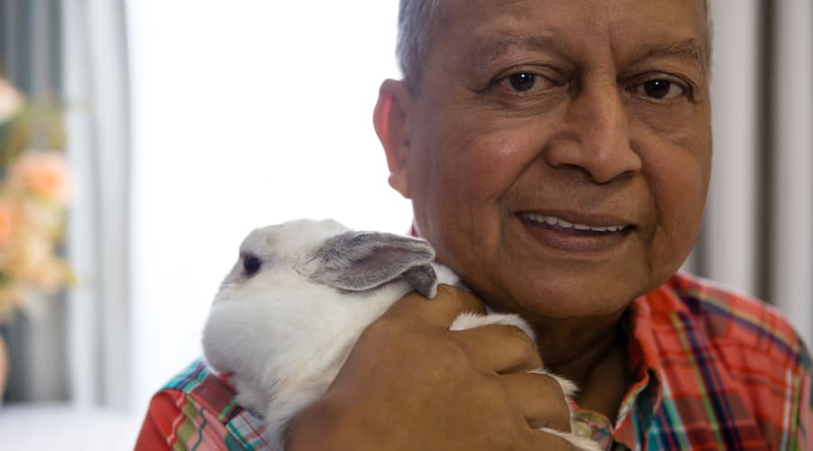 Resident smiling and holding a visiting rabbit at Cascade Park Vista Assisted Living in Tacoma, Washington