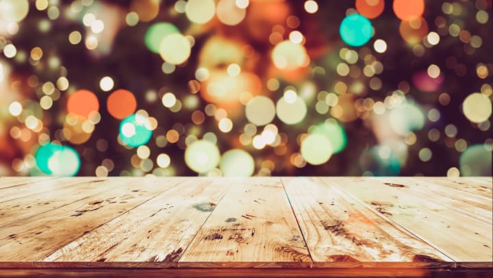 Wood plank foreground with festive red, green, and gold lights in the background
