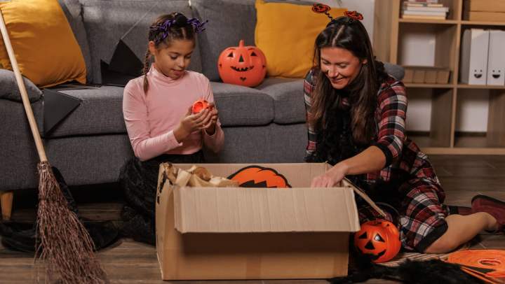 A mother and daughter unpack Halloween decorations in their living room.