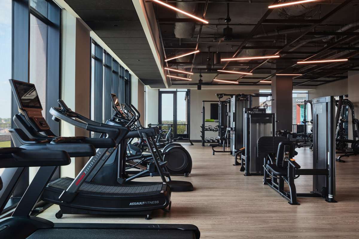Fitness center with large windows and fitness equipment at The Novus Apartments in Durham, North Carolina