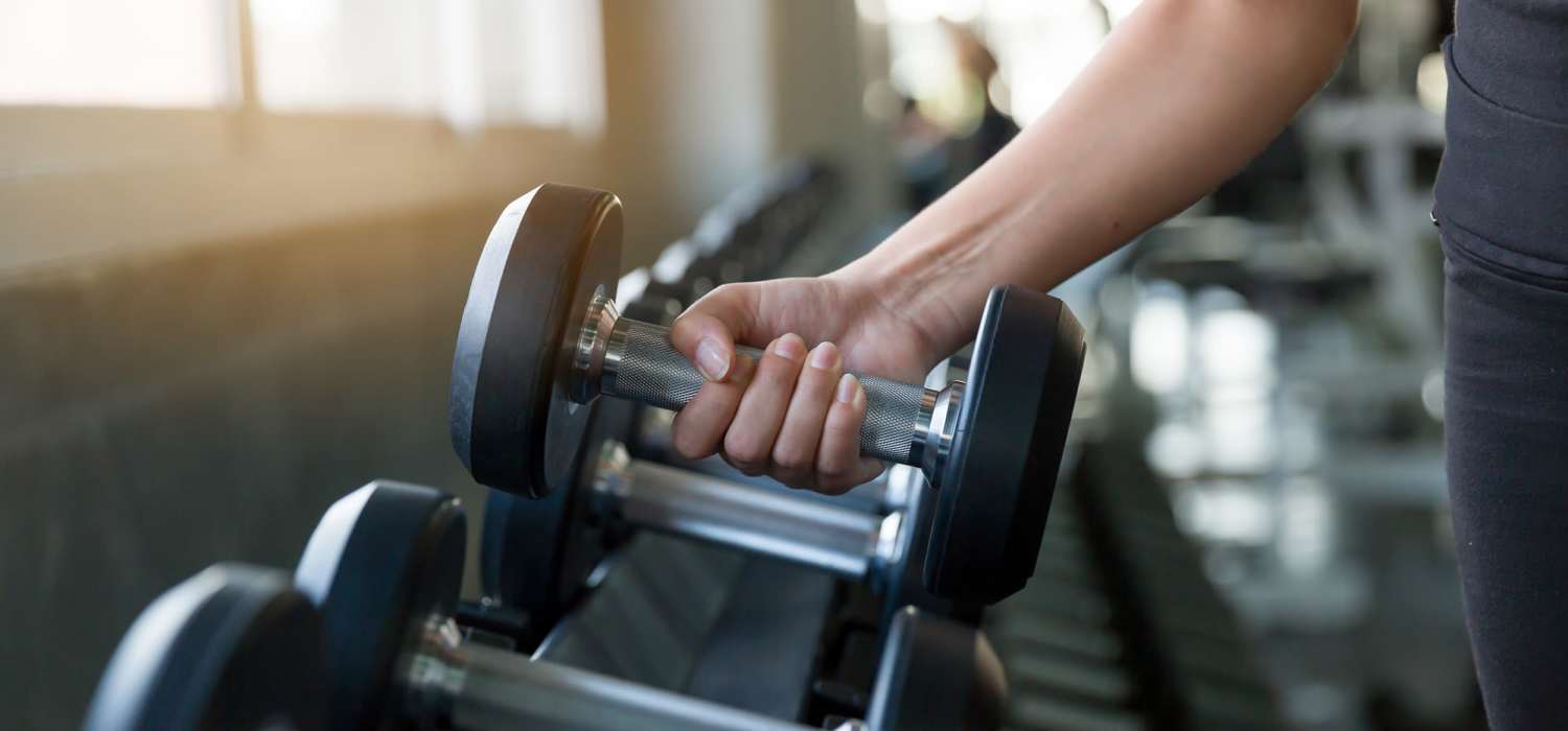 Resident lifting dumbbell in fitness center at Walnut Trace in Raleigh, North Carolina