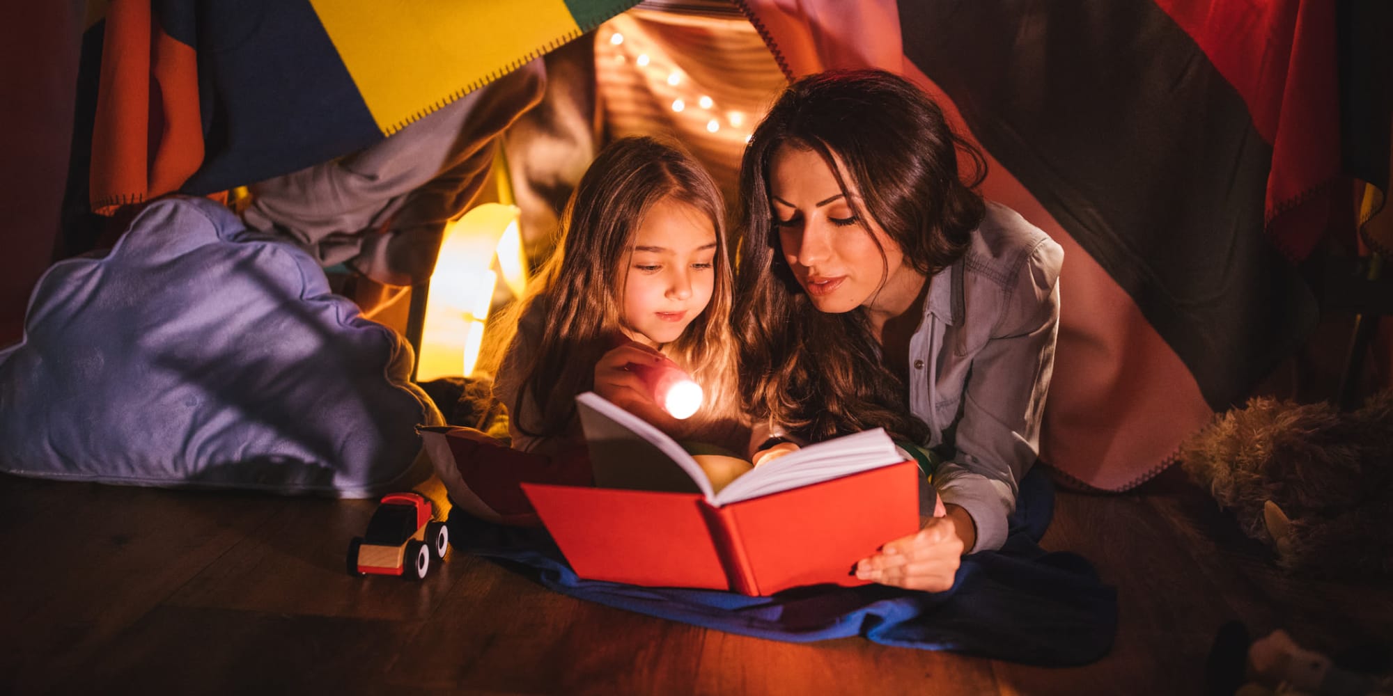 Mother reading to her daughter in a blanket fort at Uplund in Kirkland, Washington