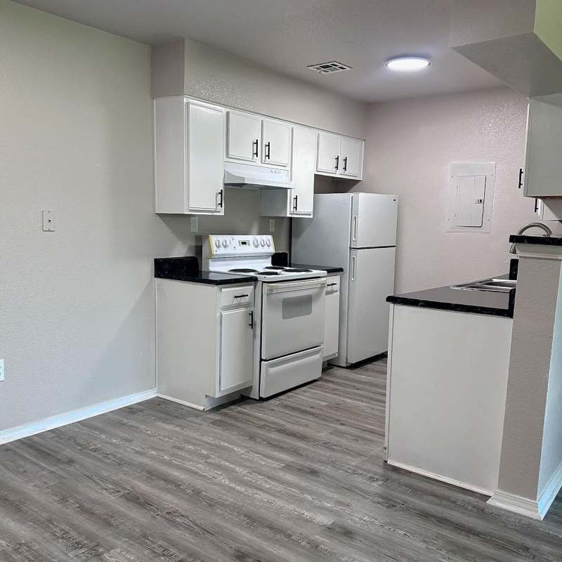 Fully equipped kitchen with granite countertops stainless steel appliances like a refrigerator, stove, and drawer microwave at The Gardens At Pryor Creek in Pryor, Oklahoma