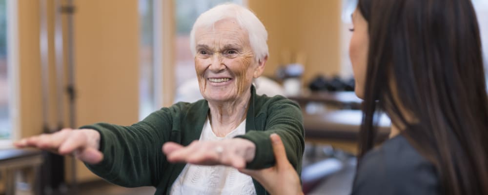 A staff member assisting a resident in exercising at Chateau Gardens Memory Care in Springfield, Oregon