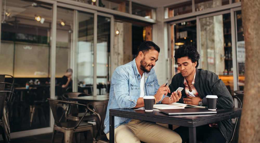 Two friends with a cup of coffee working at a cafe near Maple Manor Apartments in Lebanon, Tennessee