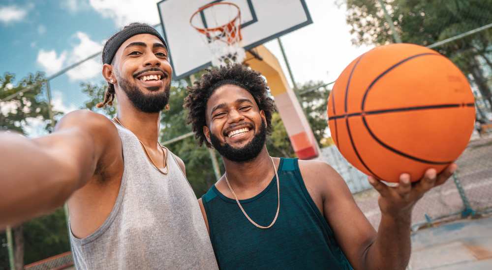 Men smiling with basketball at court near WaterWalk Jacksonville - Deerwood Park in Jacksonville, Florida 