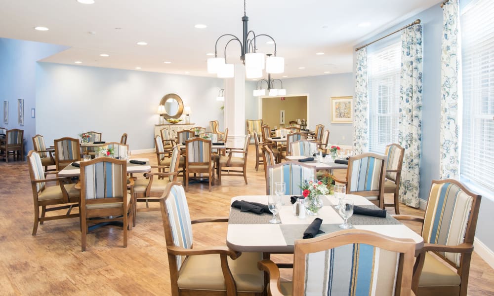 A large dining room with set tables at Keystone Place at Richland Creek in O'Fallon, Illinois