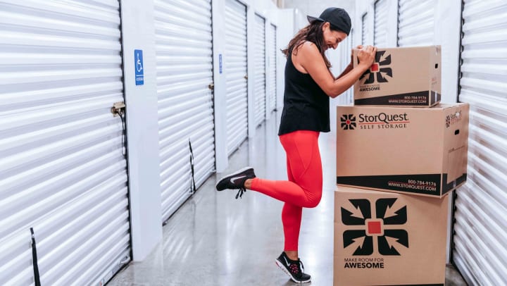 A woman balancing against storage boxes inside a self storage facility hallway