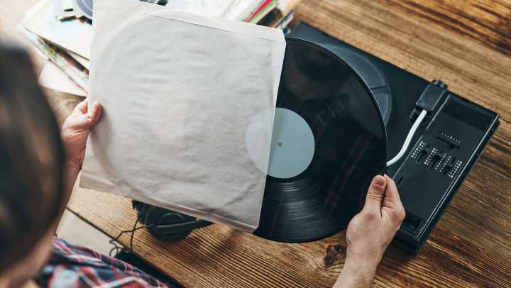 Man putting a vinyl record in its sleeve after using it