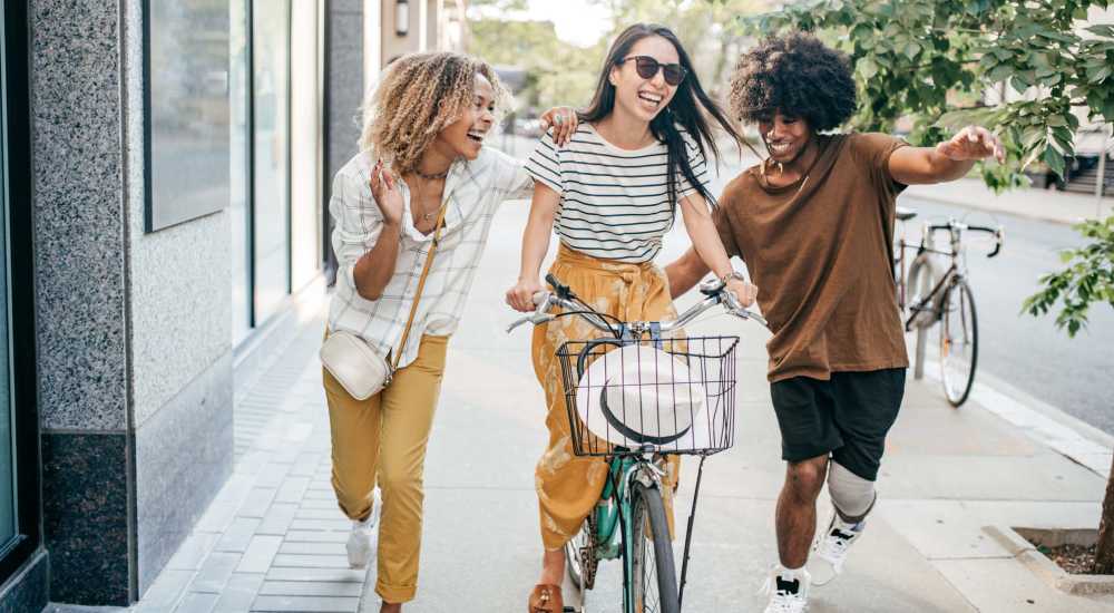 Friends enjoying a day out, biking and laughing on the street at Bellwood Gateway Apartments in Bellwood, Illinois 