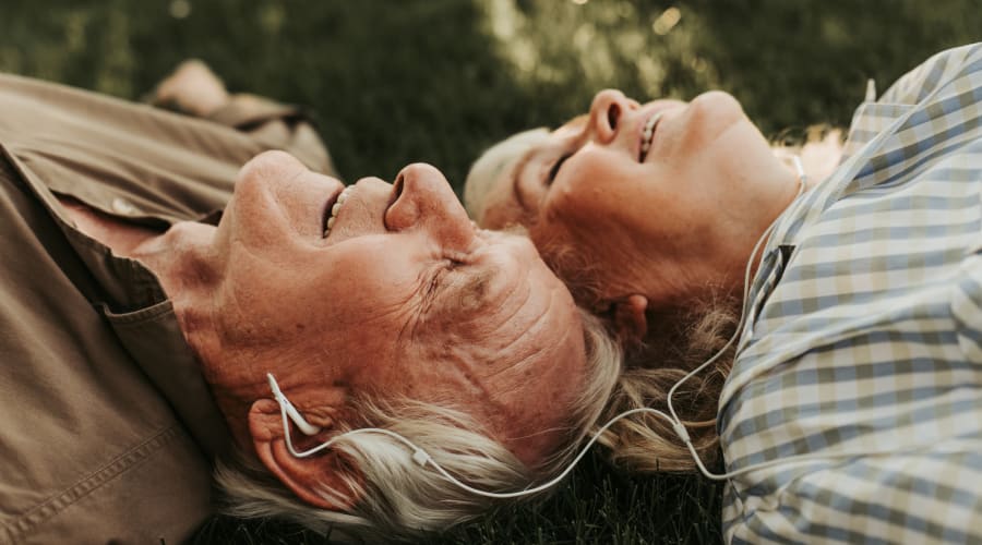 Resident couple lying on the grass outside on a beautiful day at Peoples Senior Living in Tacoma, Washington