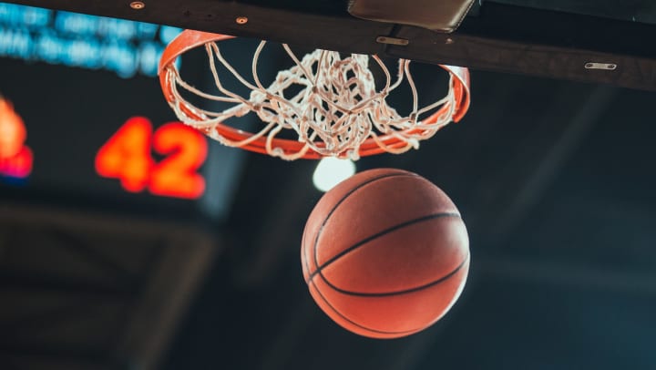 Basketball swishing through a hoop in an arena