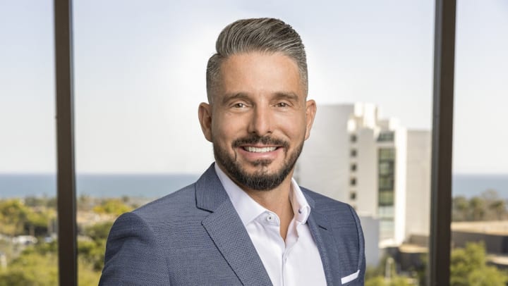 Portrait of Olympus founder, Chandler Wonderly smiling while wearing a white dress shirt and a blue blazer.