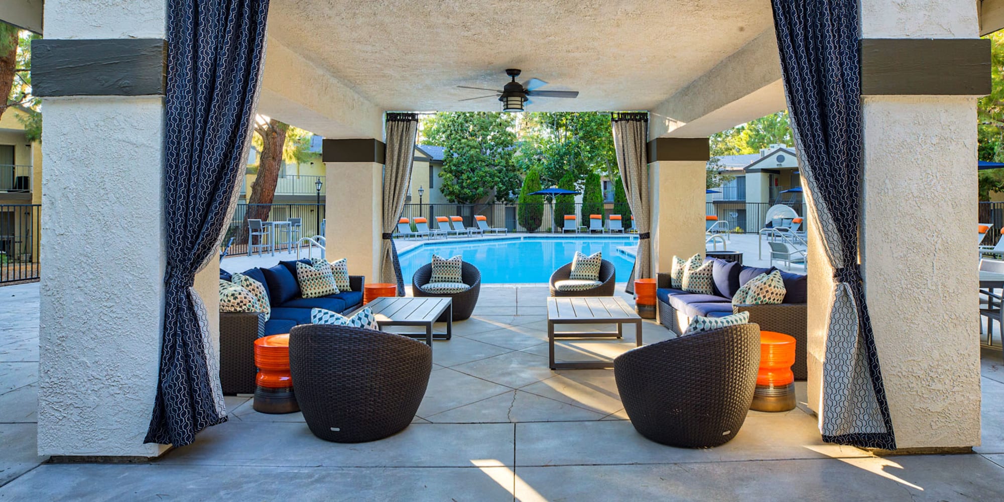 Covered outdoor lounge area with a ceiling fan near the pool at Mountain Vista in Victorville, California