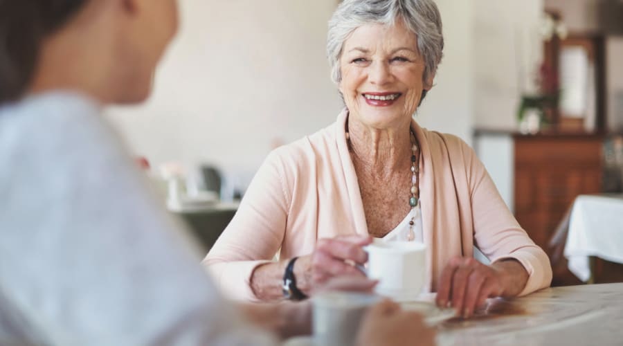 Adult day health senior chatting with a caregiver over tea at Peoples Senior Living in Tacoma, Washington 