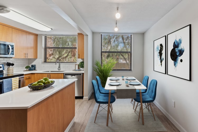 Dining area and modern kitchen with an island at Bull Run Apartments in Miami Lakes, Florida